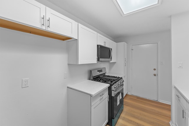 kitchen with black gas range oven, white cabinetry, and light hardwood / wood-style floors