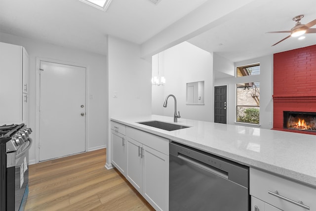 kitchen with black gas range oven, sink, light hardwood / wood-style floors, white cabinets, and stainless steel dishwasher