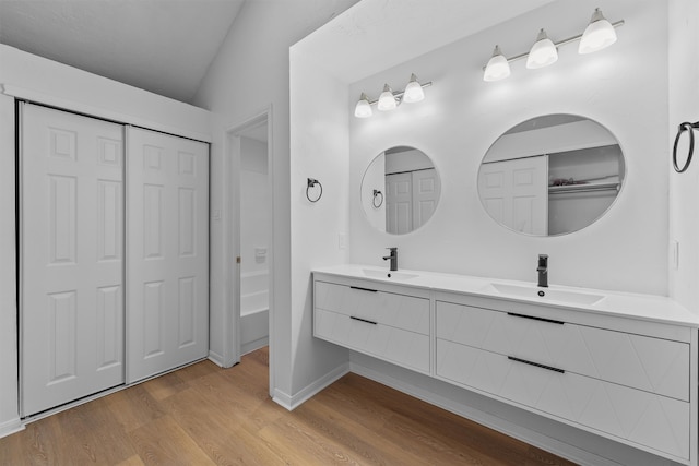 bathroom with hardwood / wood-style floors, lofted ceiling, and vanity