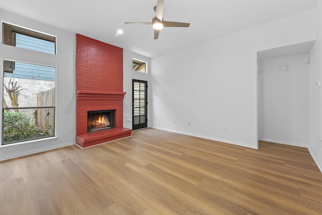 unfurnished living room featuring a fireplace, light hardwood / wood-style floors, and ceiling fan