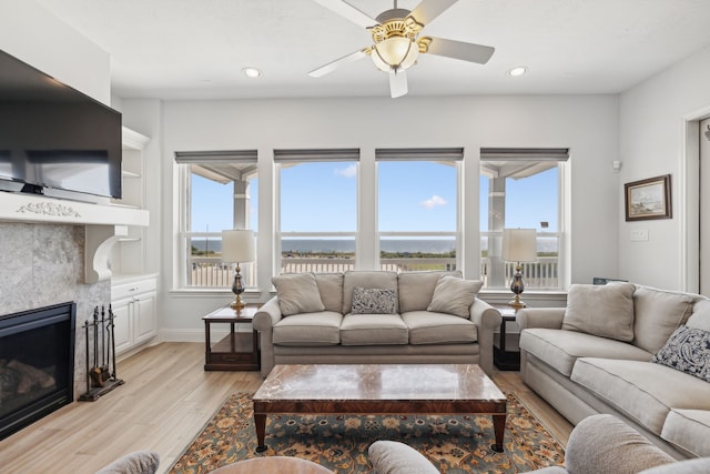 living room featuring light hardwood / wood-style floors, ceiling fan, and a tiled fireplace