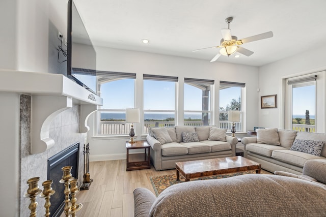 living room with a fireplace, light hardwood / wood-style floors, and ceiling fan