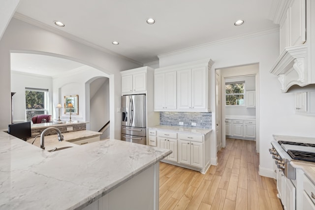 kitchen with light stone counters, appliances with stainless steel finishes, decorative backsplash, light hardwood / wood-style floors, and white cabinets