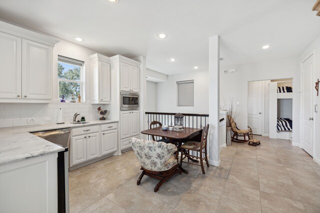 kitchen featuring stainless steel appliances, sink, tasteful backsplash, light stone countertops, and white cabinets