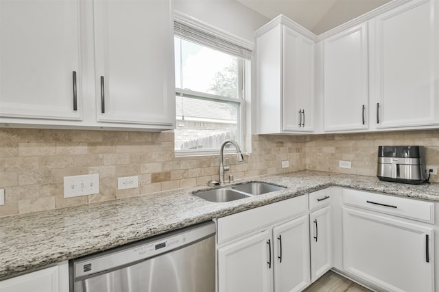 kitchen featuring light stone counters, white cabinets, sink, stainless steel dishwasher, and backsplash