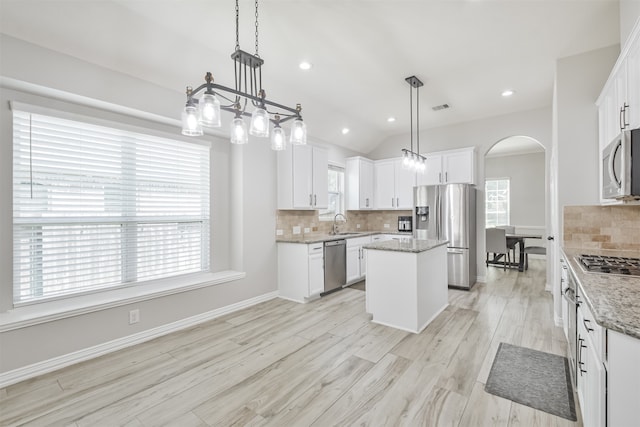 kitchen featuring stainless steel appliances, light hardwood / wood-style flooring, a center island, white cabinets, and pendant lighting