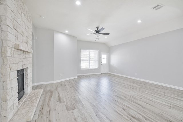 unfurnished living room with a stone fireplace, light hardwood / wood-style flooring, lofted ceiling, and ceiling fan