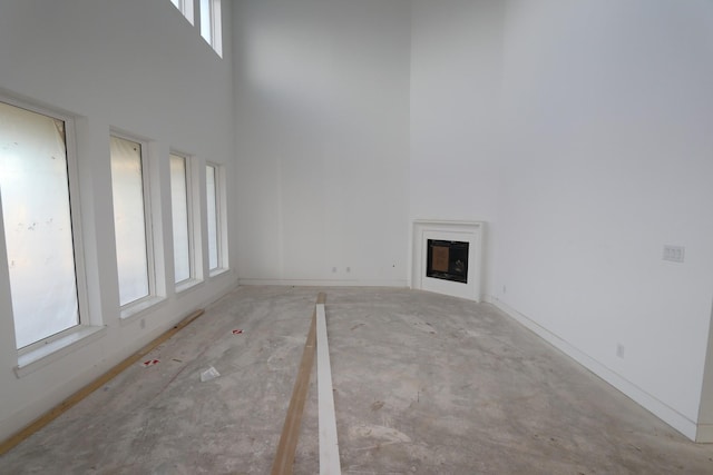 unfurnished living room with a high ceiling, a fireplace, and baseboards