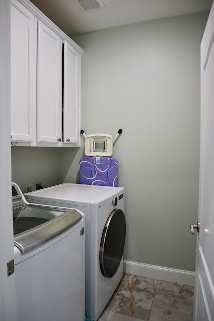 clothes washing area with separate washer and dryer and cabinets