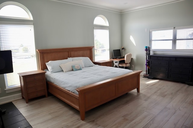 bedroom featuring multiple windows, crown molding, and light hardwood / wood-style flooring