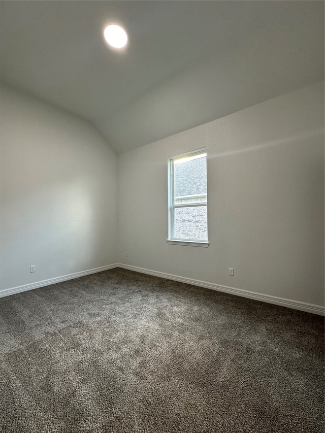 carpeted spare room with vaulted ceiling