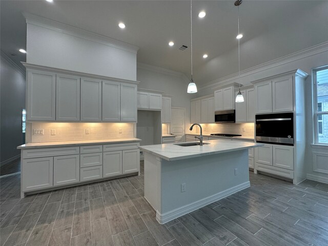 kitchen featuring hardwood / wood-style flooring, a center island with sink, sink, and appliances with stainless steel finishes