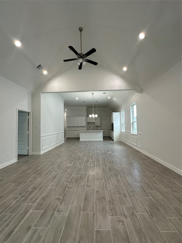 unfurnished living room with hardwood / wood-style floors, vaulted ceiling, ornamental molding, and ceiling fan with notable chandelier