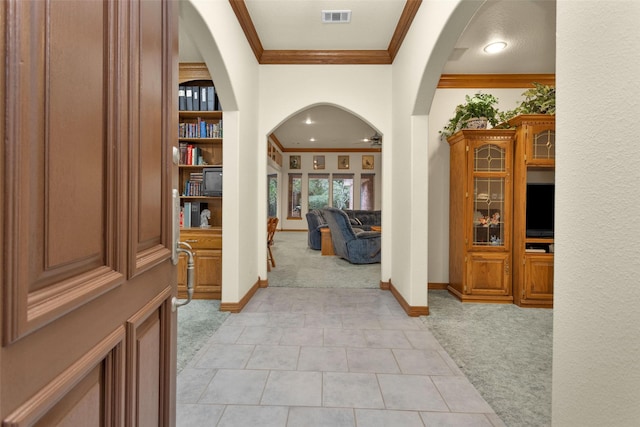 entryway with ornamental molding, arched walkways, light carpet, and visible vents