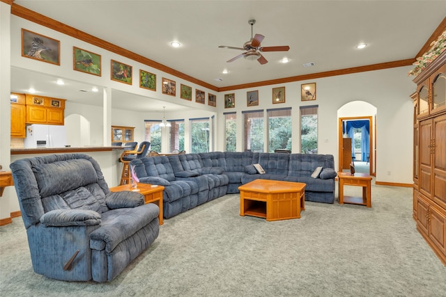 living area featuring light carpet, baseboards, ornamental molding, and arched walkways