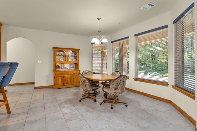 dining space featuring baseboards, visible vents, arched walkways, and a chandelier