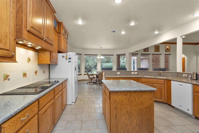 kitchen with tasteful backsplash, white appliances, a sink, and brown cabinets