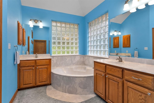 bathroom with two vanities, a sink, and a bath