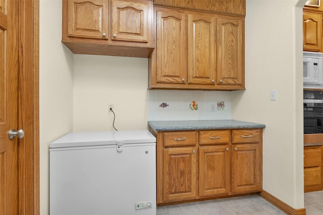 kitchen with tasteful backsplash, white appliances, and brown cabinetry