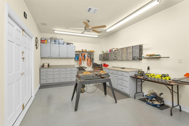 interior space featuring concrete flooring, visible vents, baseboards, a ceiling fan, and a workshop area