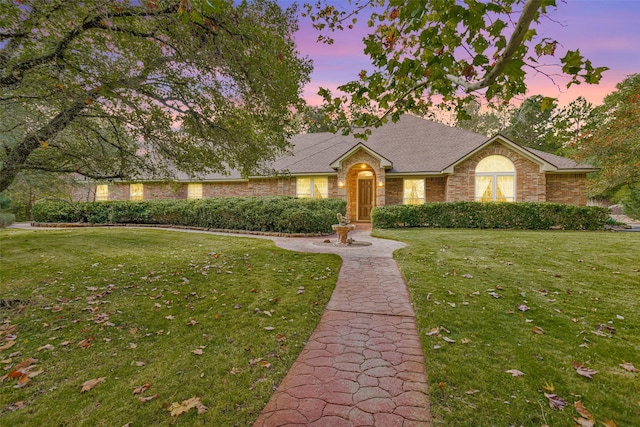 single story home with a front yard, brick siding, and roof with shingles