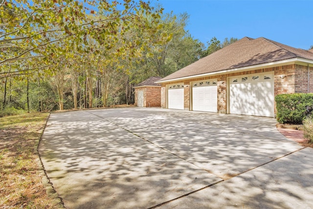 view of home's exterior featuring a garage, driveway, roof with shingles, and brick siding