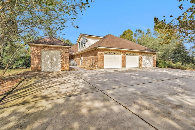 view of front of house with roof with shingles, concrete driveway, and brick siding