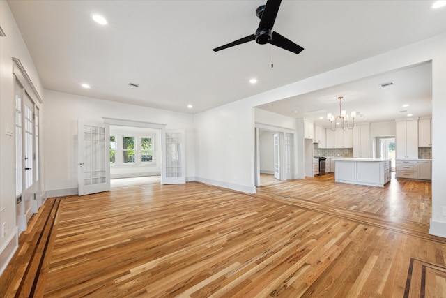 unfurnished living room with french doors, light hardwood / wood-style floors, and ceiling fan with notable chandelier