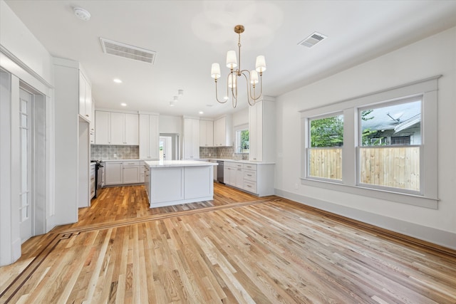 kitchen featuring light hardwood / wood-style flooring, white cabinetry, decorative light fixtures, and a center island