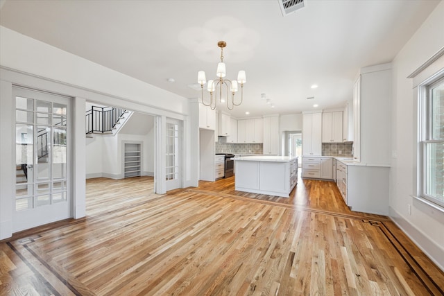 kitchen featuring a kitchen island, white cabinetry, light hardwood / wood-style floors, and plenty of natural light