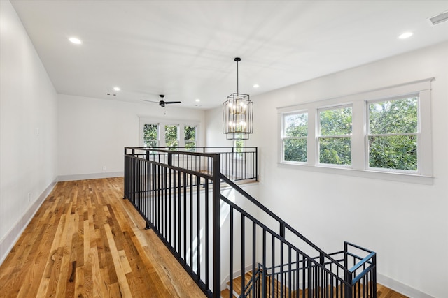 corridor featuring a wealth of natural light, an inviting chandelier, and hardwood / wood-style flooring