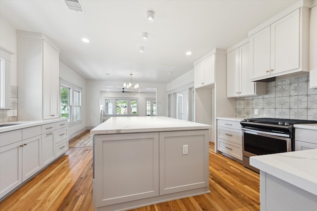 kitchen with white cabinetry, an inviting chandelier, stainless steel range, light hardwood / wood-style floors, and a center island