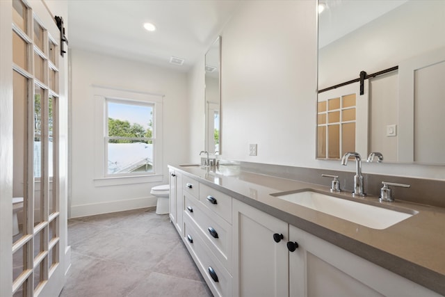 bathroom with toilet, vanity, and tile patterned flooring