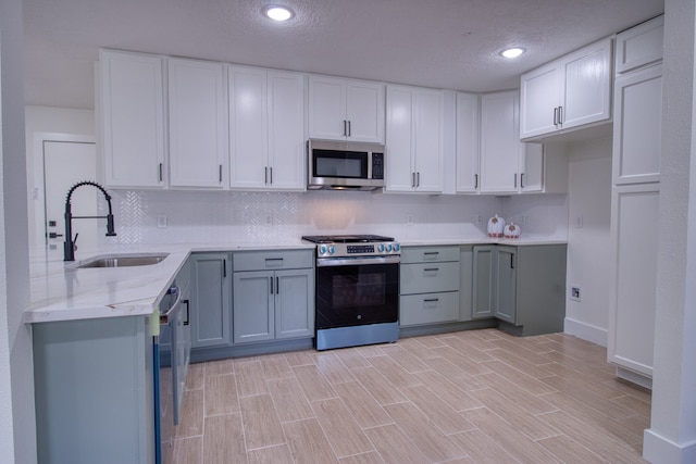 kitchen featuring a textured ceiling, white cabinetry, sink, and stainless steel appliances