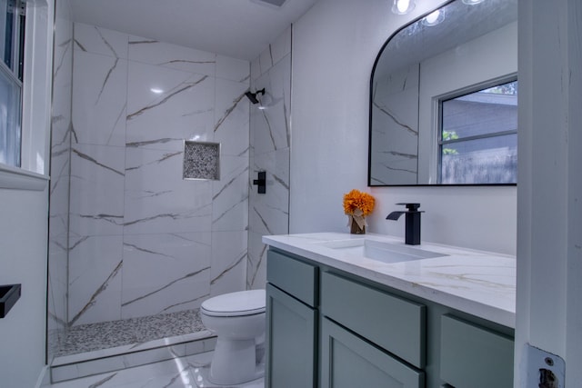 bathroom with toilet, vanity, and tiled shower