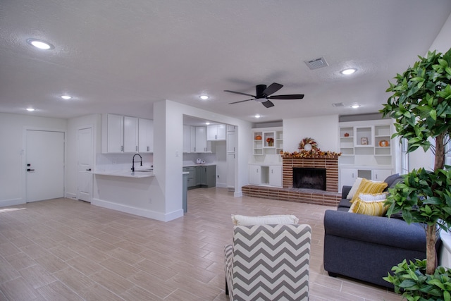 living room featuring light hardwood / wood-style flooring, sink, ceiling fan, and a textured ceiling