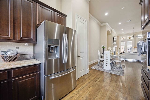 kitchen with stainless steel fridge with ice dispenser, backsplash, light hardwood / wood-style floors, dark brown cabinets, and ornamental molding