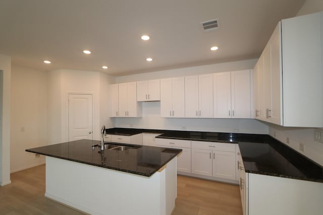 kitchen with a center island with sink, white cabinetry, light hardwood / wood-style floors, and sink