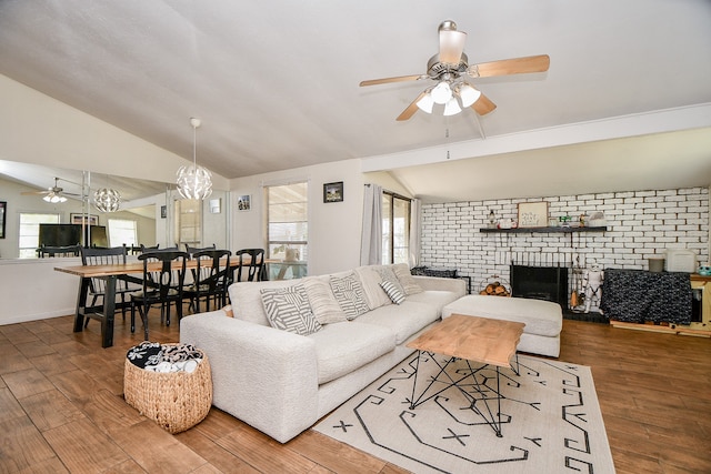 living room featuring hardwood / wood-style floors, a brick fireplace, lofted ceiling, ceiling fan, and brick wall