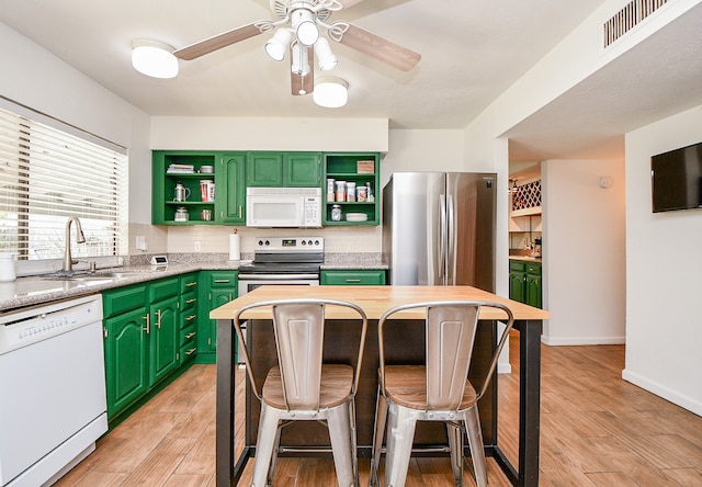 kitchen featuring stainless steel appliances, green cabinets, sink, tasteful backsplash, and light wood-type flooring