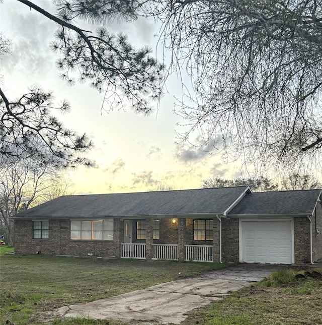 ranch-style home featuring a porch, a garage, and a yard