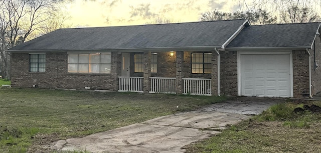 ranch-style home featuring a lawn, covered porch, and a garage