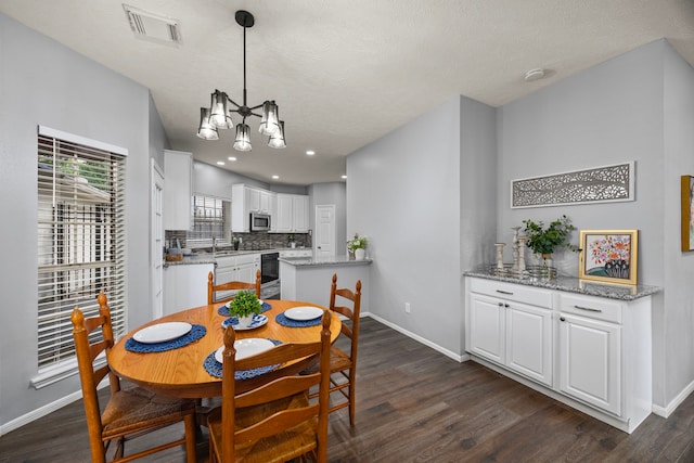 dining area with dark wood-type flooring, a textured ceiling, and a notable chandelier