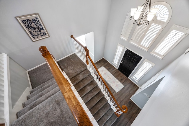 stairs featuring hardwood / wood-style floors, a towering ceiling, and a chandelier