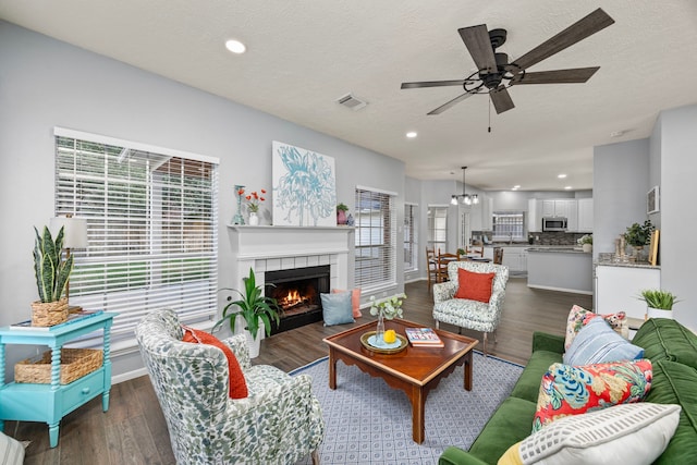 living room featuring a wealth of natural light, ceiling fan, a tile fireplace, and dark hardwood / wood-style flooring