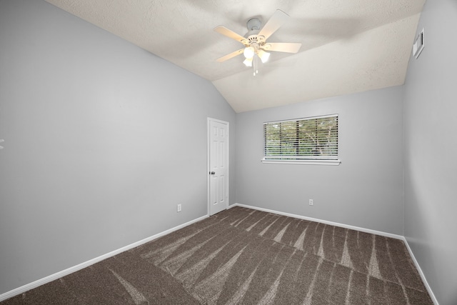 empty room with ceiling fan, a textured ceiling, vaulted ceiling, and dark carpet