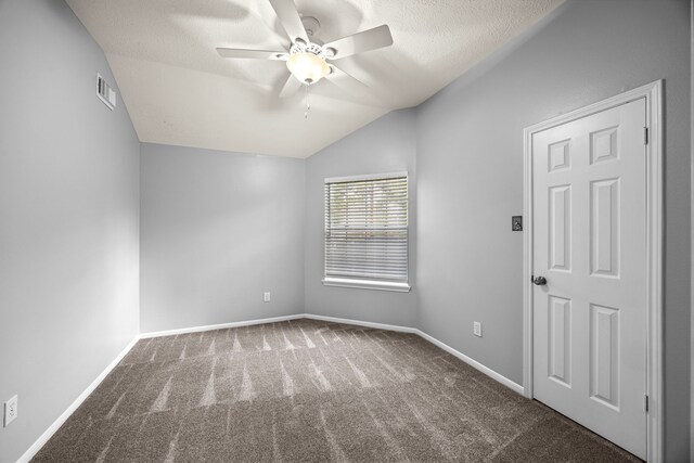 unfurnished room with ceiling fan, a textured ceiling, lofted ceiling, and dark carpet