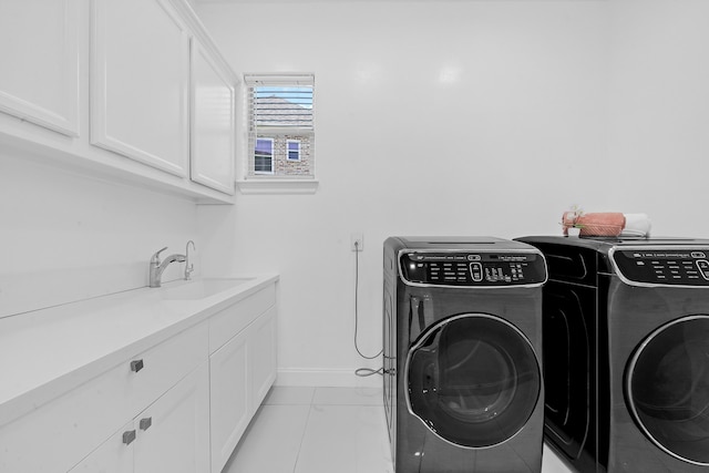 clothes washing area featuring cabinets, sink, and washer and clothes dryer