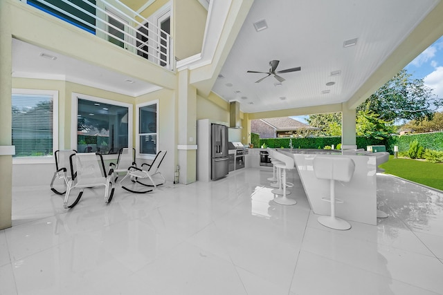 view of patio / terrace featuring exterior bar, an outdoor kitchen, area for grilling, and ceiling fan