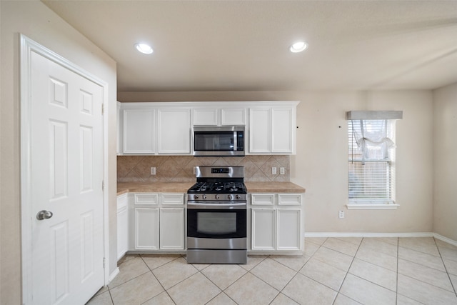 kitchen with white cabinets, decorative backsplash, light tile patterned floors, and stainless steel appliances